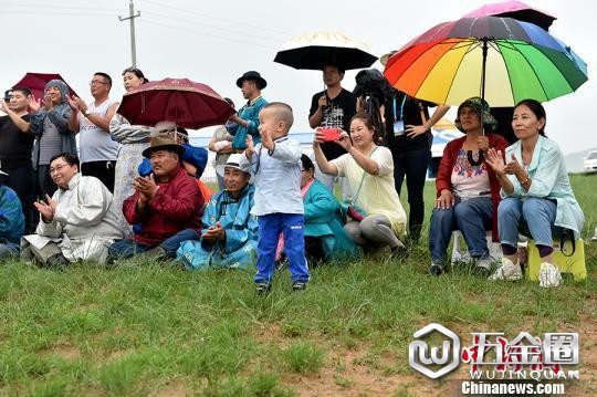 图为牧民在雨中观看乌兰牧骑演出。 翟璐 摄