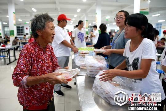 8月24日,志愿者在潍坊寿光市营里镇第二初级中学安置点为灾民发放救援物资。 梁犇 摄
